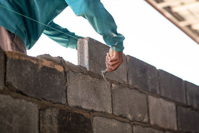 Low angle view of man holding stone wall