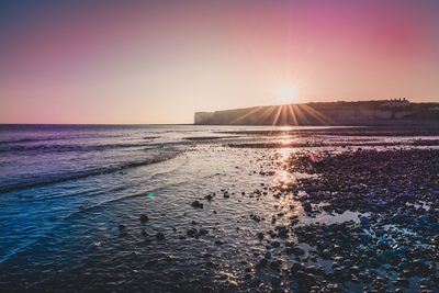 Sun shining over sea during sunset