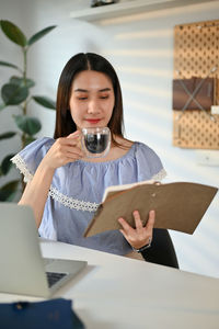 Young woman using mobile phone while sitting on table