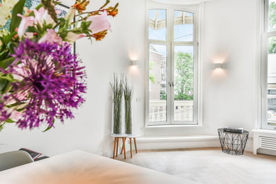 Flower vase on table by window at home