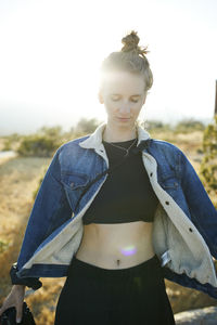 Young woman standing on field against sky