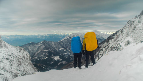 Rear view of hikers standing on snowcapped mountain