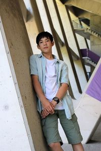 Portrait of young man standing against staircase