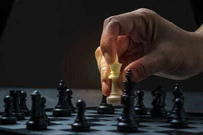 Full length of man playing with chess against black background