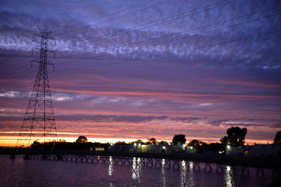 Silhouette electricity pylon against sky during sunset