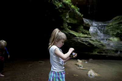 Girl holding stone while standing by steam
