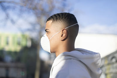 Close-up portrait of young man looking away against sky