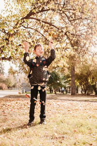 Boy in a jacket scatters leaves in the autumn park. the child rejoices at the autumn leaves. 