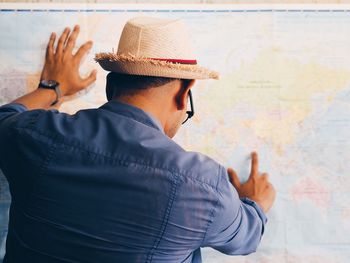 Rear view of man pointing on world map