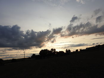 Silhouette trees on field against sky during sunset