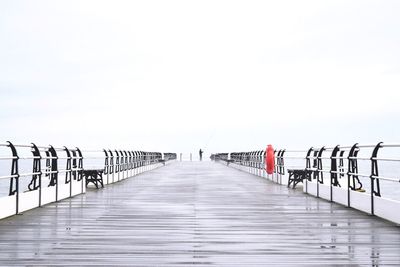 Pier over sea with person fishing in background