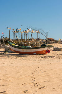 Boats moored on beach against clear sky