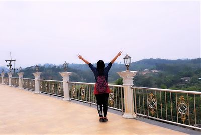 Rear view of woman standing on footbridge