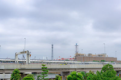 Bridge over factory against sky in city