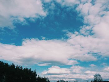 Low angle view of trees against cloudy sky