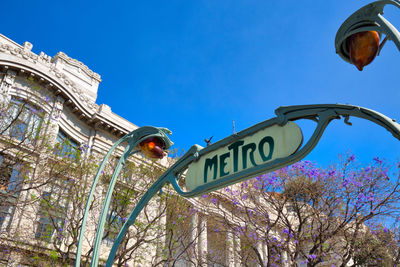 Low angle view of road sign against blue sky