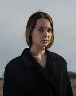 Portrait of beautiful young woman standing against sky