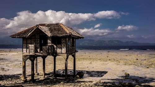 House on beach by sea against sky.