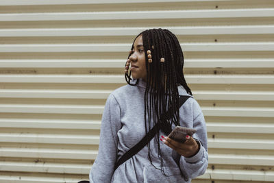 Full length of young woman standing against wall