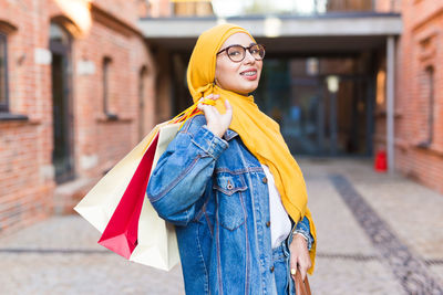 Smiling young woman standing on street in city