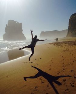 Man jumping at beach during sunny day