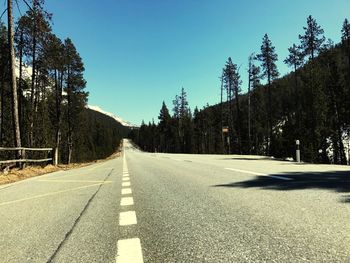 Road amidst trees against clear sky