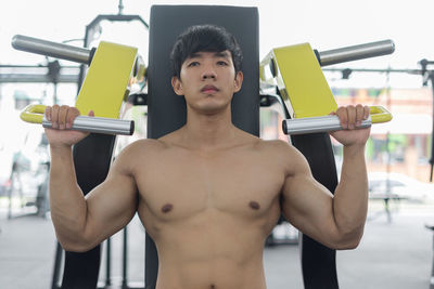 Portrait of shirtless man exercising in gym