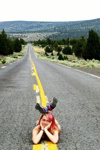 Full length of teenage girl lying on country road