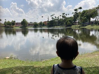 Rear view of boy in lake against sky