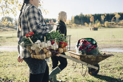 Midsection of man holding basket while standing on field