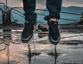 Low section of man standing on puddle