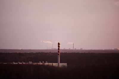 Smoke emitting from chimney on field against sky