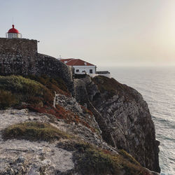 Lighthouse by sea against sky