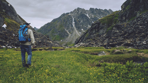 Rear view of man standing on mountain against sky