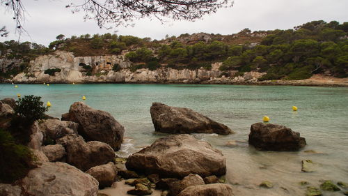 Rocks at sea shore against mountains