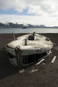 Abandoned boat on beach against sky