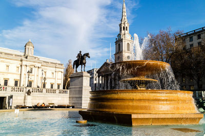 Statue of fountain in city against sky