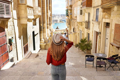 Back view of traveler woman descends stairs in the historic city of valletta, unesco heritage, malta
