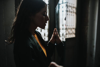 Side view of young woman holding mirror