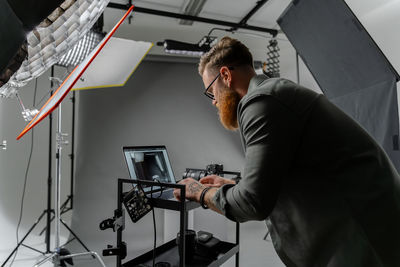 Professional photographer adjusting laptop, while preparing for shooting