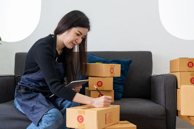 Side view of young woman sitting on sofa at home