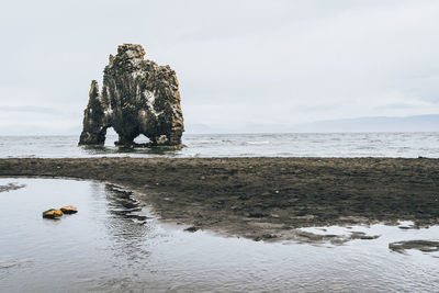 Scenic view of rock formation on beach against sky