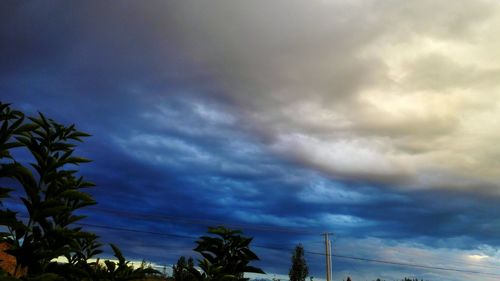 Low angle view of power lines against cloudy sky