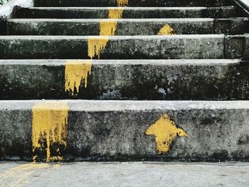 Yellow arrow symbol on brick wall