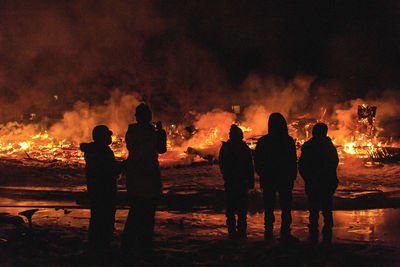 Silhouette people against fire at night