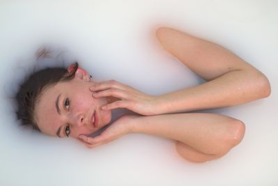 Portrait of young woman lying down against white background