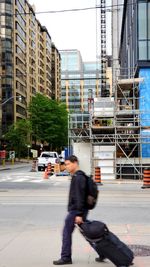 Man walking on city street against modern buildings