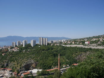 Panoramic view of buildings in city against clear blue sky