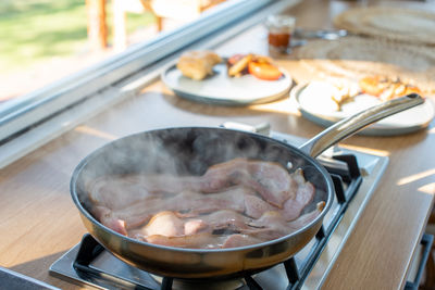 Cooking bacons for breakfast in the morning sunlight.