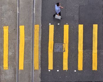 High angle view of man walking by zebra crossing on street